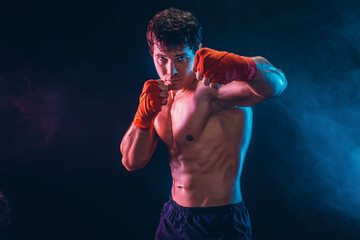 Portrait of Aggressive shirtless boxer who preparing for fight on dark background. Sport concept