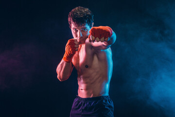 Front view of aggressive boxer who training and practicing jab on smoke background. Sport concept