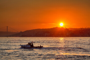 Obraz premium A small boat floats on the sea against the backdrop of the rising sun. Travel to Istanbul, Turkey.