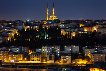 Night view of the illuminated city, the illuminated houses and the mosque. Lights are on in the windows. Journey to istanbul