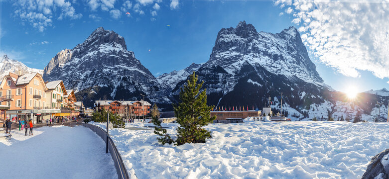 Winter overview of the north face of the Eiger as seen from the mountain village of Grindelwald, Switzerland. Paragliders fly over Grindwald.