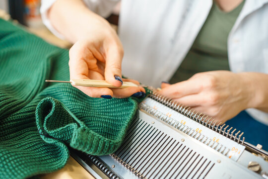 the person is engaged in knitting on a household knitting machine. handmade