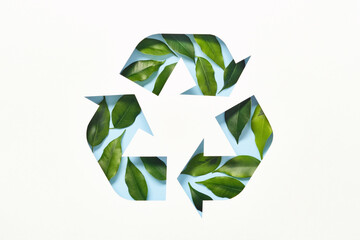 Recycle symbol made of cut paper and green leaves on blue background. Reuse, reduce, recycle concept