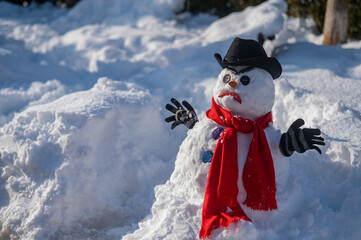 A snowman with a creepy grimace in a hat and scarf.