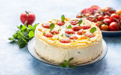Savoury cheesecake with tomatoes decorated with mint, blue background.