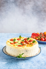 Savoury cheesecake with tomatoes decorated with mint, blue background.