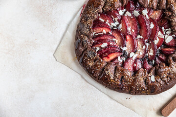 Homemade galette or open pie with chocolate, plum and almond on light background. Top view.