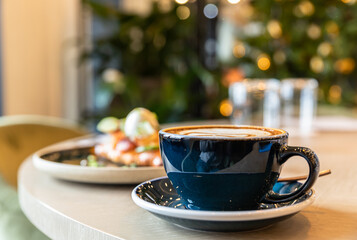 Breakfast or brunch with croissant, salmon, poached egg and cucumber with a cup of coffee. Morning in cafe or coffee shop. Lifestyle.