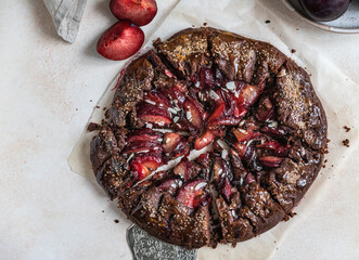 Homemade galette or open pie with chocolate, plum and almond on light background. Top view.
