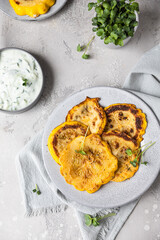 Fried patisson or yellow zucchini with sauce and micro greens, grey background.