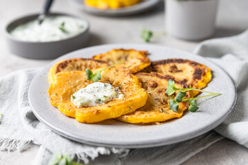 Fried patisson or yellow zucchini with sauce and micro greens, grey background.