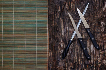 Rusty kitchen knives, Honing steel and a bamboo doily on a dark