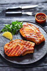 grilled bone-in pork chops on a black plate