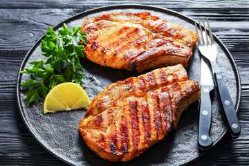 grilled bone-in pork chops on a black plate