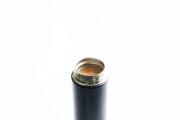 Open metal thermos or thermo mug filled with hot coffee and cream. White background. Concept of a drink for work or office. Copy space for an inscription. Selective focus