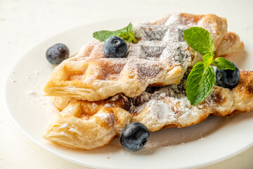 Sweet croffle in a white plate with blueberries close-up.