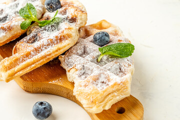 Croffle mixture of croissant and waffle in powdered sugar and with blackberries close-up.