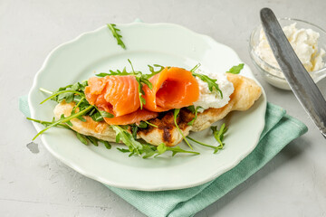 Croissant and waffles in one Croffles with salted salmon and cheese and arugula. Fish sandwich