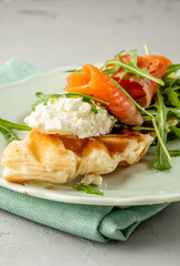 Croffles with salmon and soft cheese, arugula in a plate close-up. Croissant and waffle in one dish.