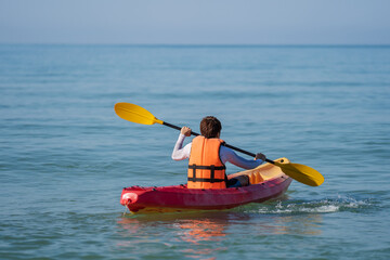 man in life jacket paddling a kayak boat in sea