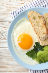 Plate of tasty breakfast on white wooden background