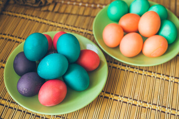 Fototapeta na wymiar Bright multicolored painted Easter eggs on green ceramic plates