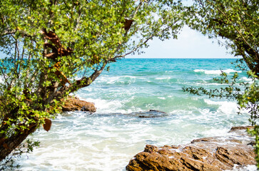 Fototapeta na wymiar Blue sea and stone with blur tree at coast. ocean shore outdoor nature landscape background. tourist travel vacation tropical summer in holidays concept.