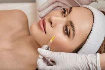 Facial skin care with treatment cosmetic oil and serum. Beautiful woman while beautician applying...