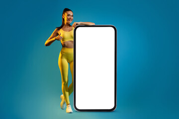 Fitness Lady Leaning On Phone Screen Gesturing Thumbs-Up, Blue Background