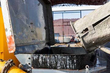 A concrete mixer truck pours mortar into a concrete pump at a construction site. Supply of concrete...