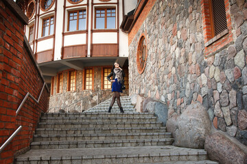 young girl stands on the stairs near the old castle