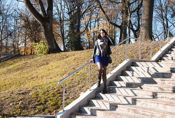 young girl stands on stairs in city park on autumn day