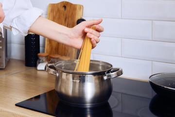 Closeup view of female hand putting pasta in boiling water