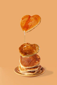 heart shaped pancakes with honey drops on beige background