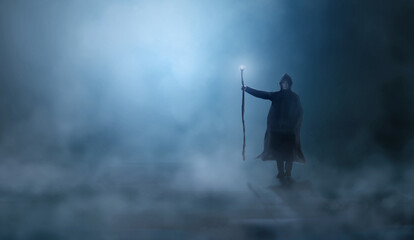 Magician in cloak, cowl with magic stick standing in fog landscape illuminated by blue moon ligh. Fantasy, wizard concept, 3D rendering - obrazy, fototapety, plakaty