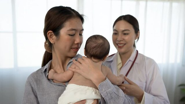 4k, Asian woman holding a newborn baby 2-month-old Asian who is sick for a female doctor Supervise and check the body in the hospital