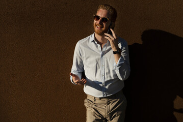 Young happy businessman outdoors. Portrait of handsome man talking to the phone.