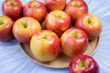 Red apple in wooden plate on wooden background, US. Red Envy apple on wooden table.