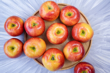 Red apple in wooden plate on wooden background, US. Red Envy apple on wooden table.