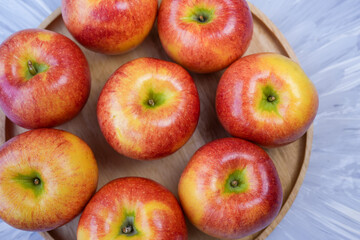 Red apple in wooden plate on wooden background, US. Red Envy apple on wooden table.