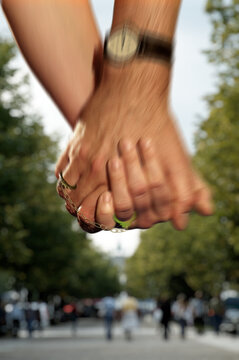 Close-up of the hands of a woman and a man with wedding rings connected with a chain. Concept of connection through marriage.