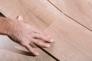 Installing laminate flooring in a room or office. Wooden parquet boards in the hands of a worker. Construction and decorative works for the finishing of housing