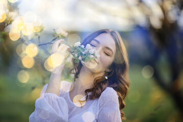 Fototapeta premium spring portrait of an adult happy woman in a blooming garden, sun rays and glare, april flowers girl