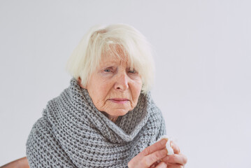 senior ill woman in scarf freezing cold at home. Health care, crisis, oldness concept