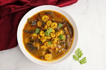 Tangy and spicy Shrimp curry. Tiny prawns curry made using dried mango and Indian spices. garnished with coriander and served with cucumber slices. Copy space.