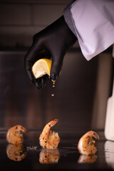 Chef's hand squeezing lemon on shrimp