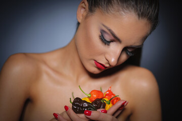 A beautiful girl holding different colours hot peppers in her hands