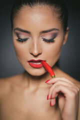 Beautiful woman biting a red hot pepper with her lips
