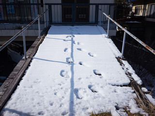 footprints on the snow-covered small bridge with handrails