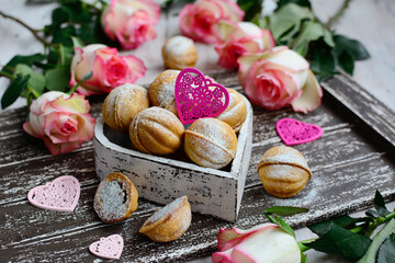 Food composition with rose flowers, cookies and decorative hearts on a wooden background. Closeup. Valentine's Day and Holidays